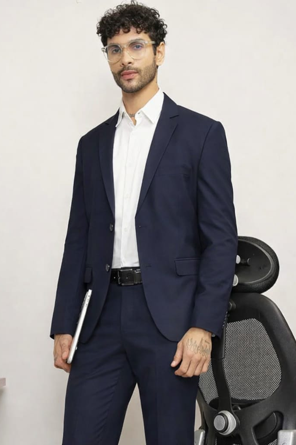 Man wearing a navy suit with a white shirt, standing against a plain background.
