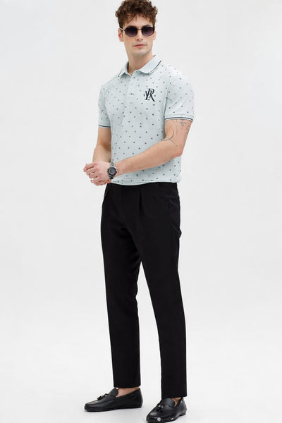 Man wearing a light gray patterned polo shirt and black pants on a white background