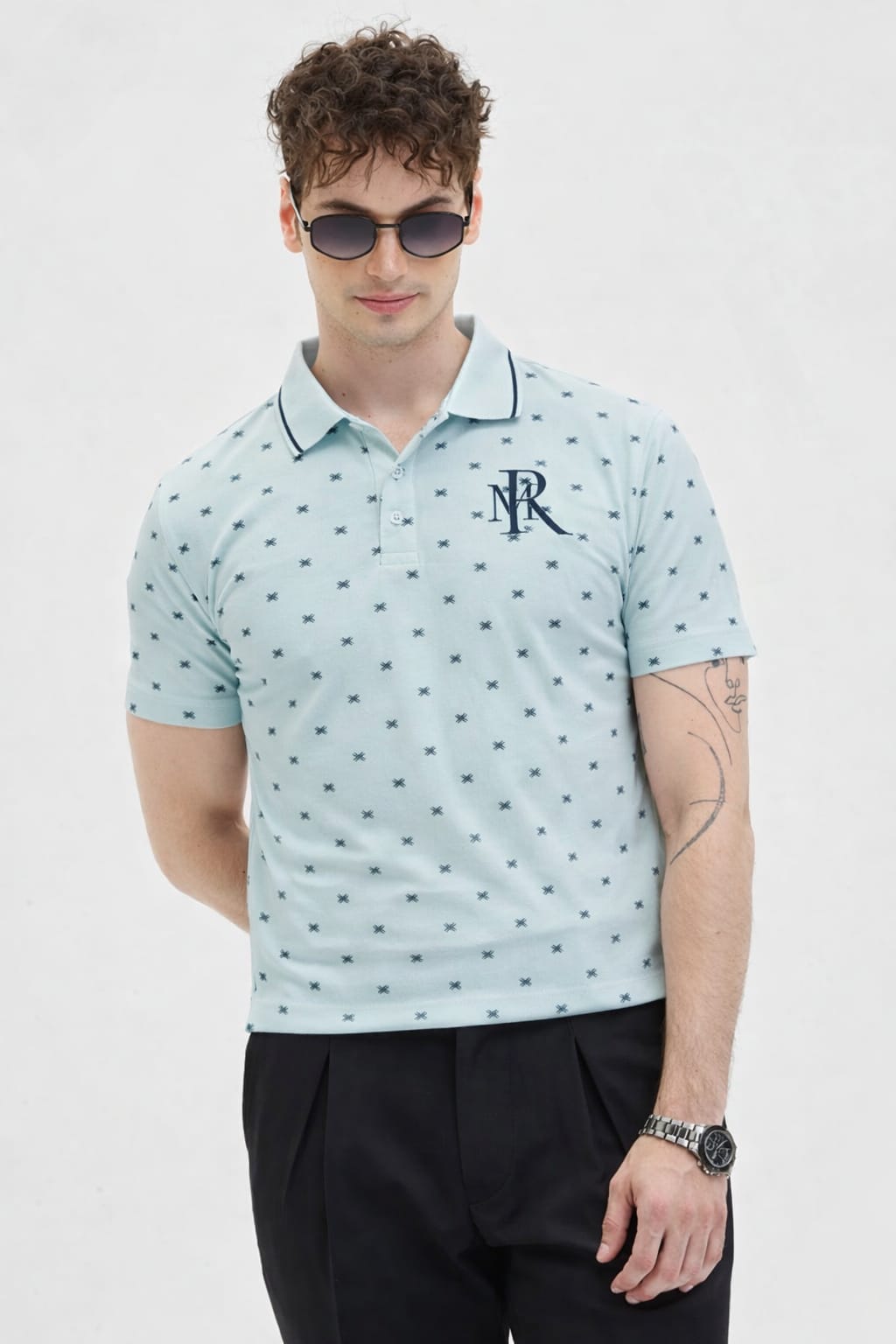 Man wearing a light blue polo shirt with a logo on a white background