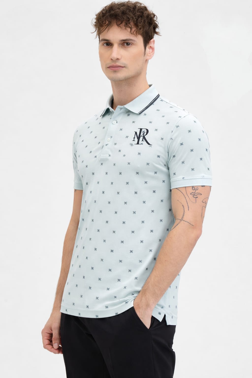 Man wearing a light blue polo shirt with a logo on a white background