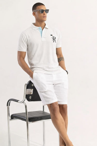 Man in white polo shirt and shorts with sunglasses, leaning against a chair on a white background