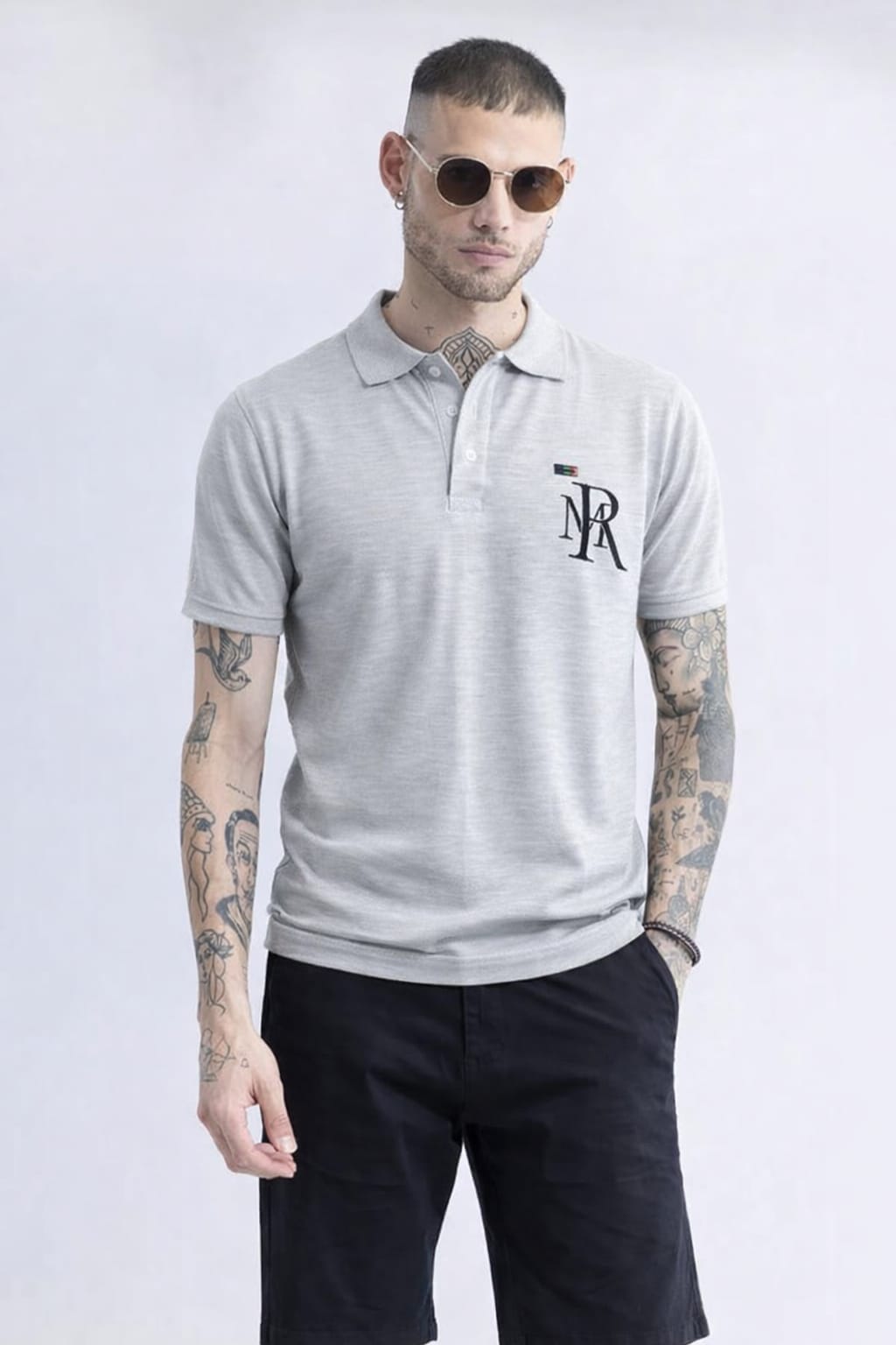 Man wearing a gray polo shirt with a logo on a white background