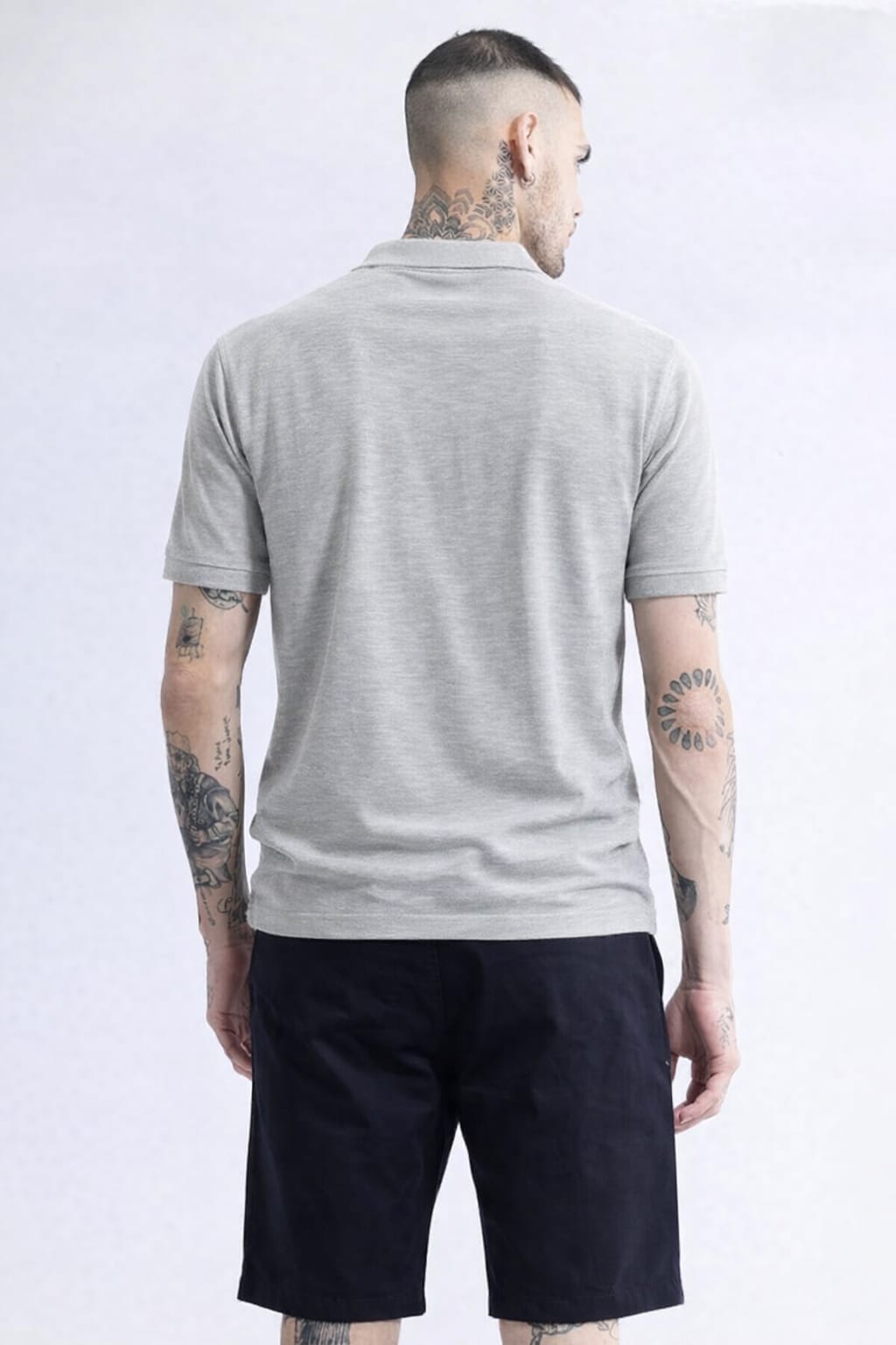 Man wearing a gray polo shirt and black shorts on a white background