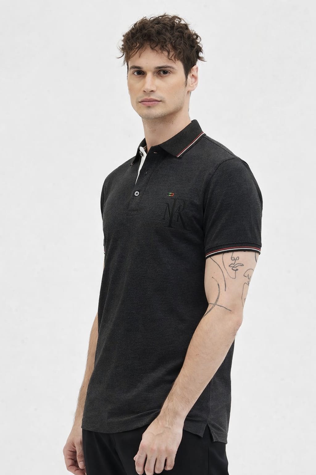 Man wearing a black polo shirt with white trim on a light gray background