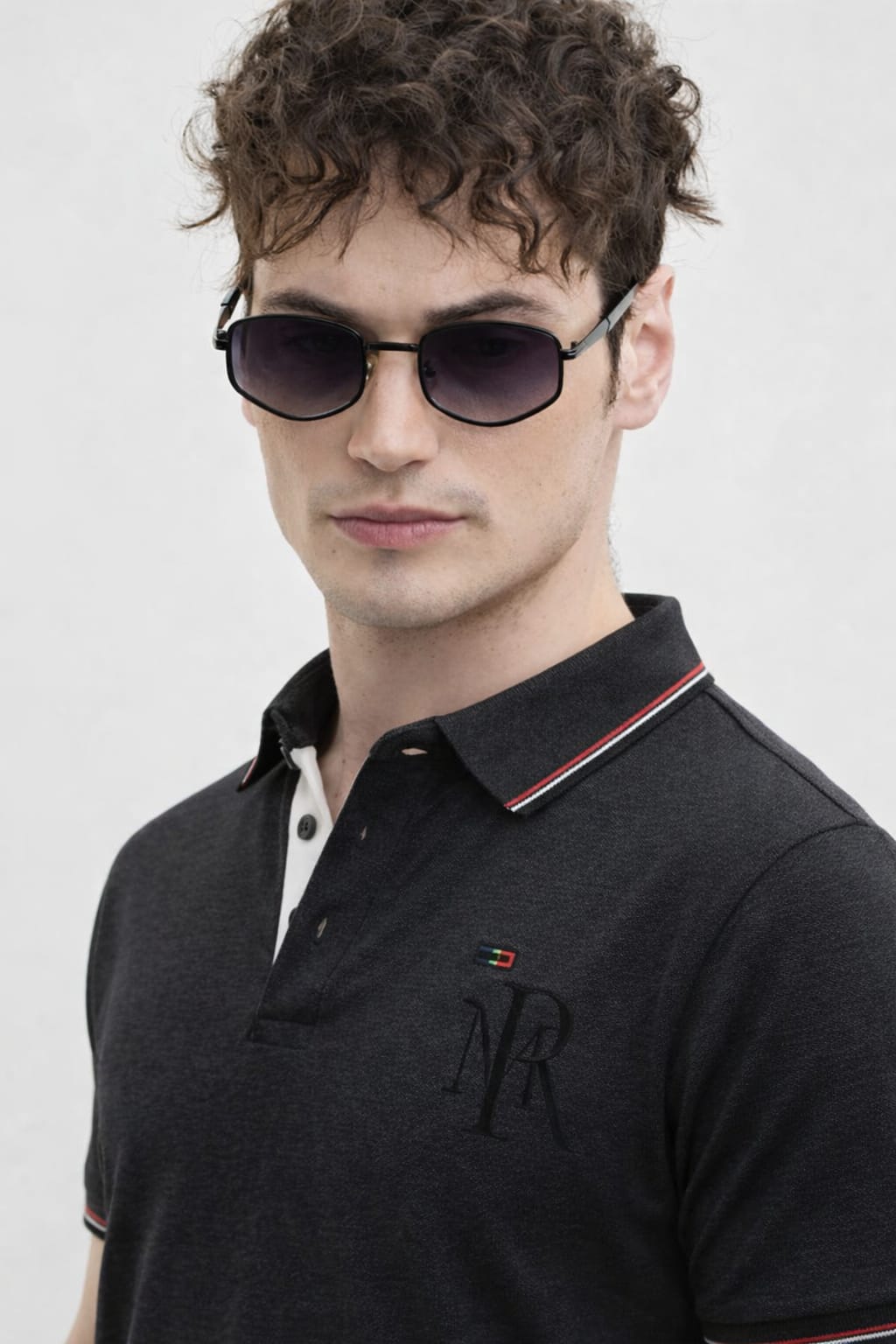 Man wearing a black polo shirt with a logo on a white background