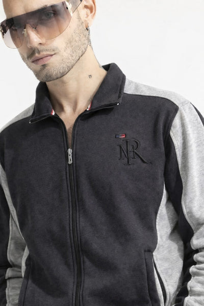 Man wearing a black and gray jacket with a logo, against a white background