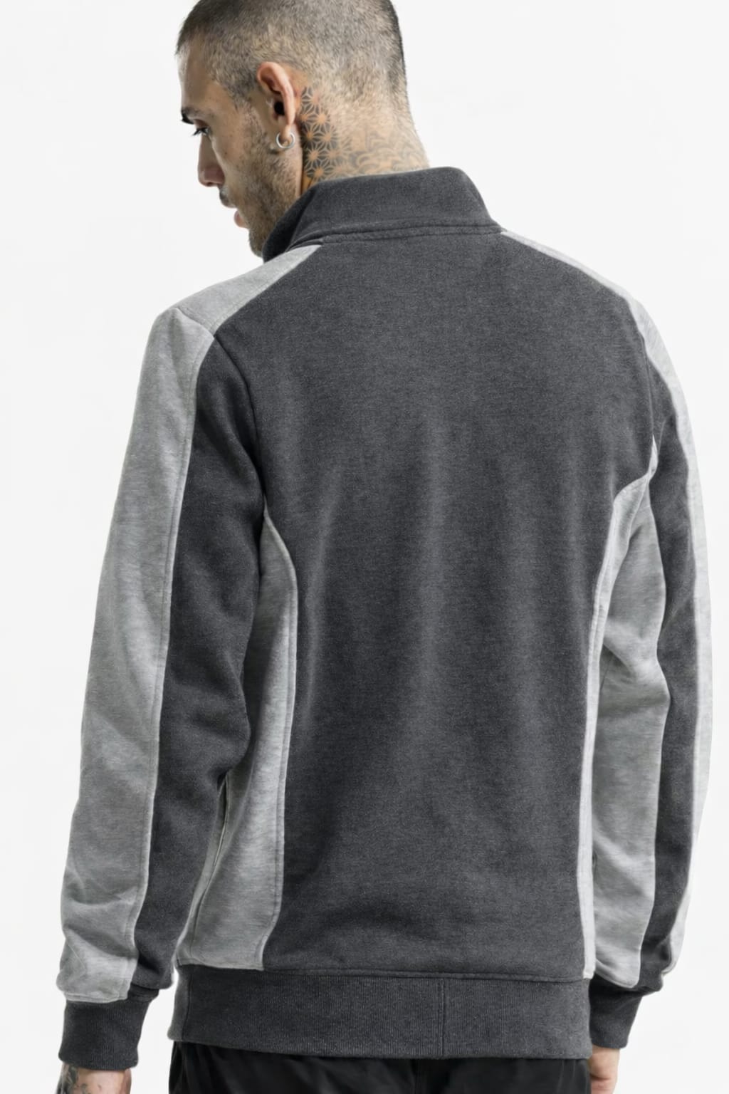 Person wearing a gray and white jacket on a plain background