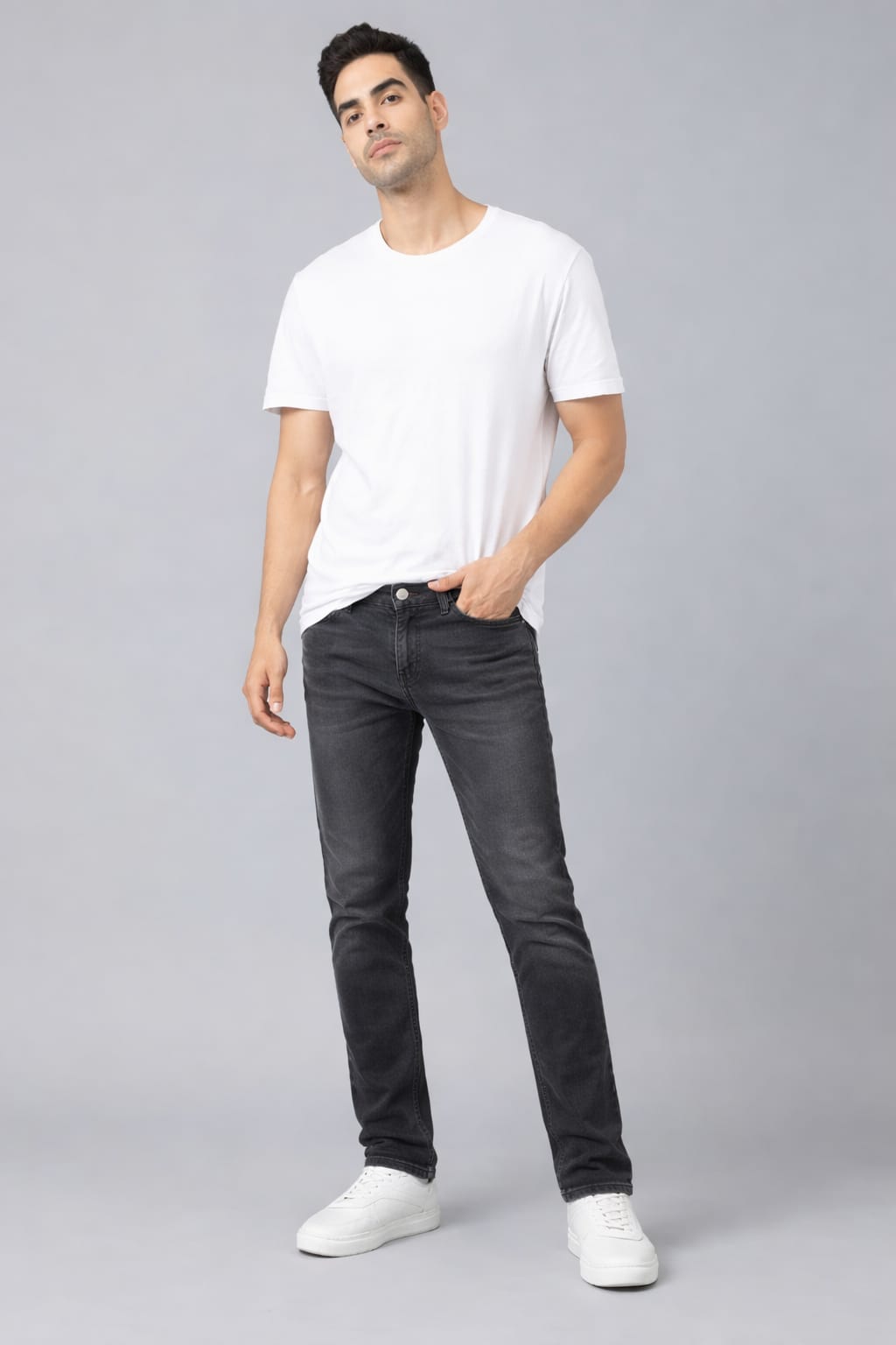 Man wearing a white t-shirt and black jeans on a gray background