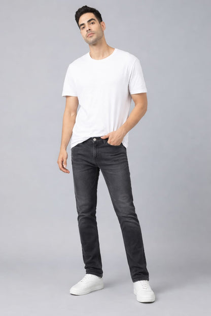 Man wearing a white t-shirt and black jeans on a gray background