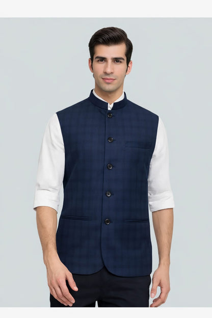 Man wearing a navy blue vest over a white shirt on a light gray background