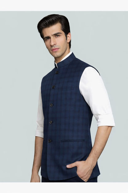 Man wearing a navy blue vest over a white shirt on a light gray background