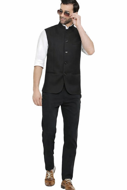Man wearing a black vest over a white shirt with black pants on a white background