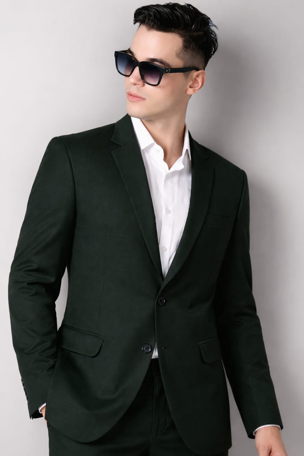 Man wearing a black suit and sunglasses against a plain background