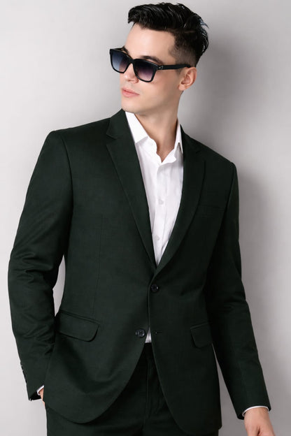 Man wearing a black suit and sunglasses against a plain background
