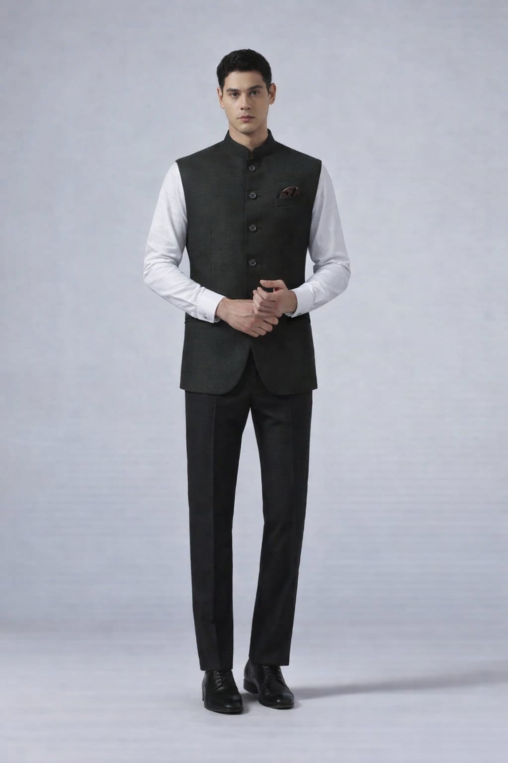 Man wearing a black suit vest over a white shirt on a gray background