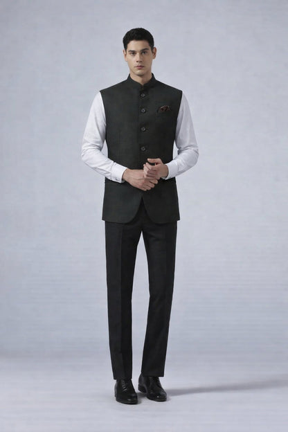 Man wearing a black suit vest over a white shirt on a gray background