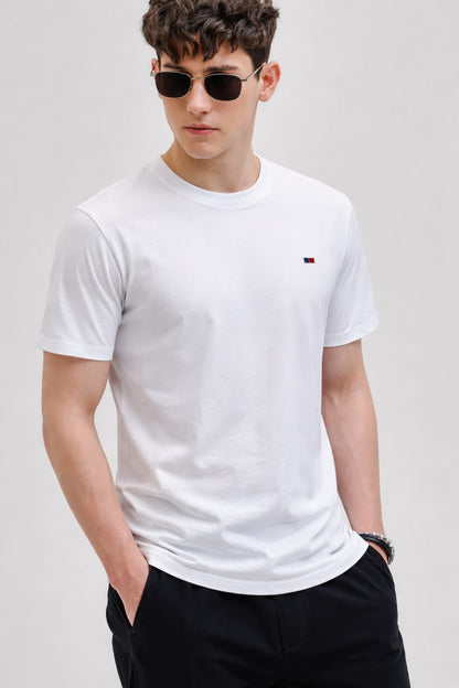 Man wearing a white t-shirt with a logo on a plain background