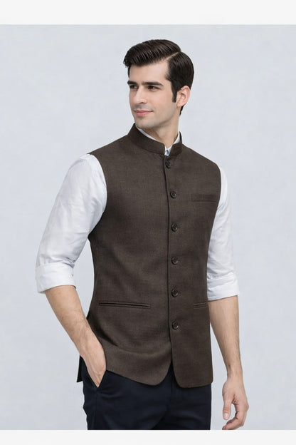 Man wearing a brown vest over a white shirt on a light gray background