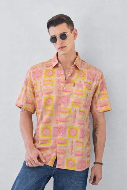 Man wearing a patterned shirt with pink and yellow design against a plain background