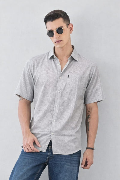 Man wearing a gray short-sleeve shirt and sunglasses against a light gray background
