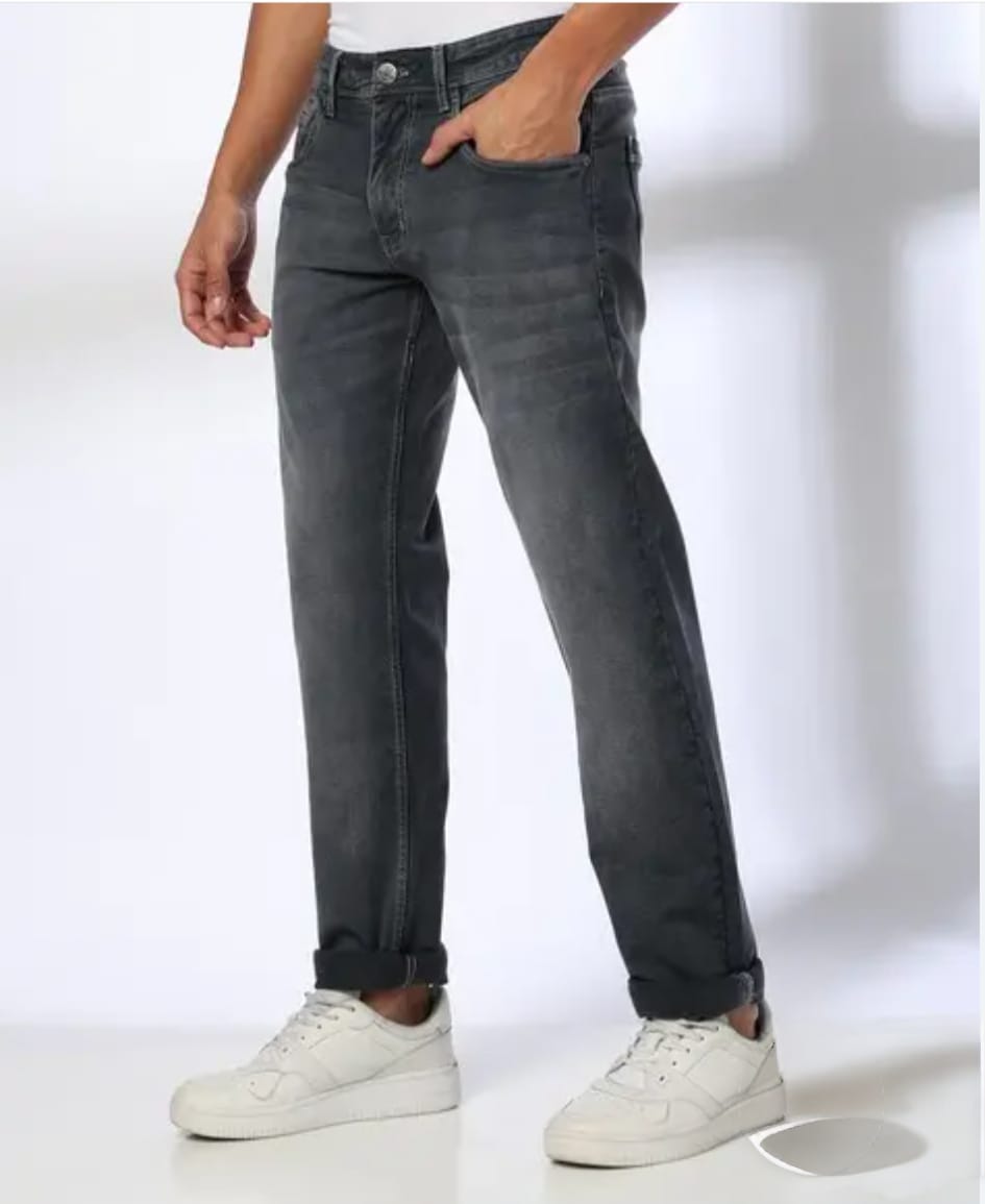 Person wearing dark gray jeans and white sneakers on a white background