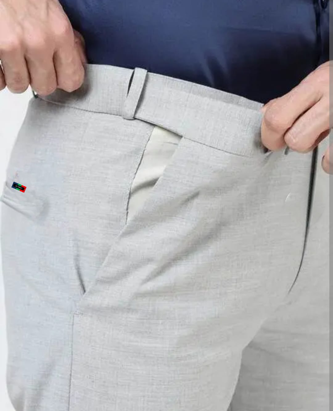 Close-up of gray pants with a brand logo on the pocket against a white background