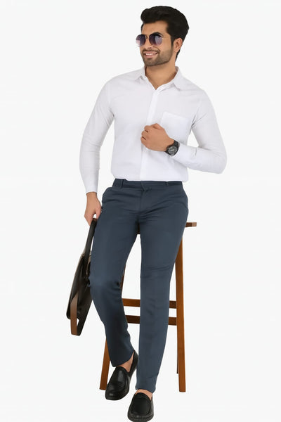 Man wearing a white shirt and gray pants sitting on a chair against a white background