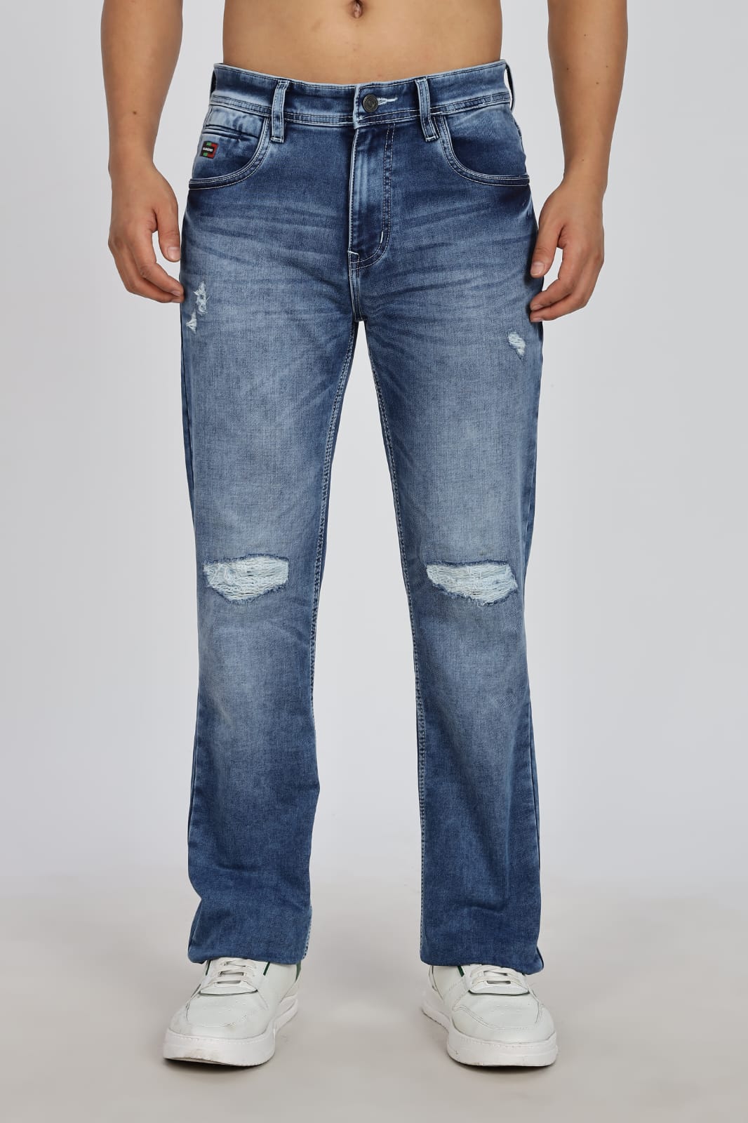 Blue distressed jeans worn by a person on a plain background