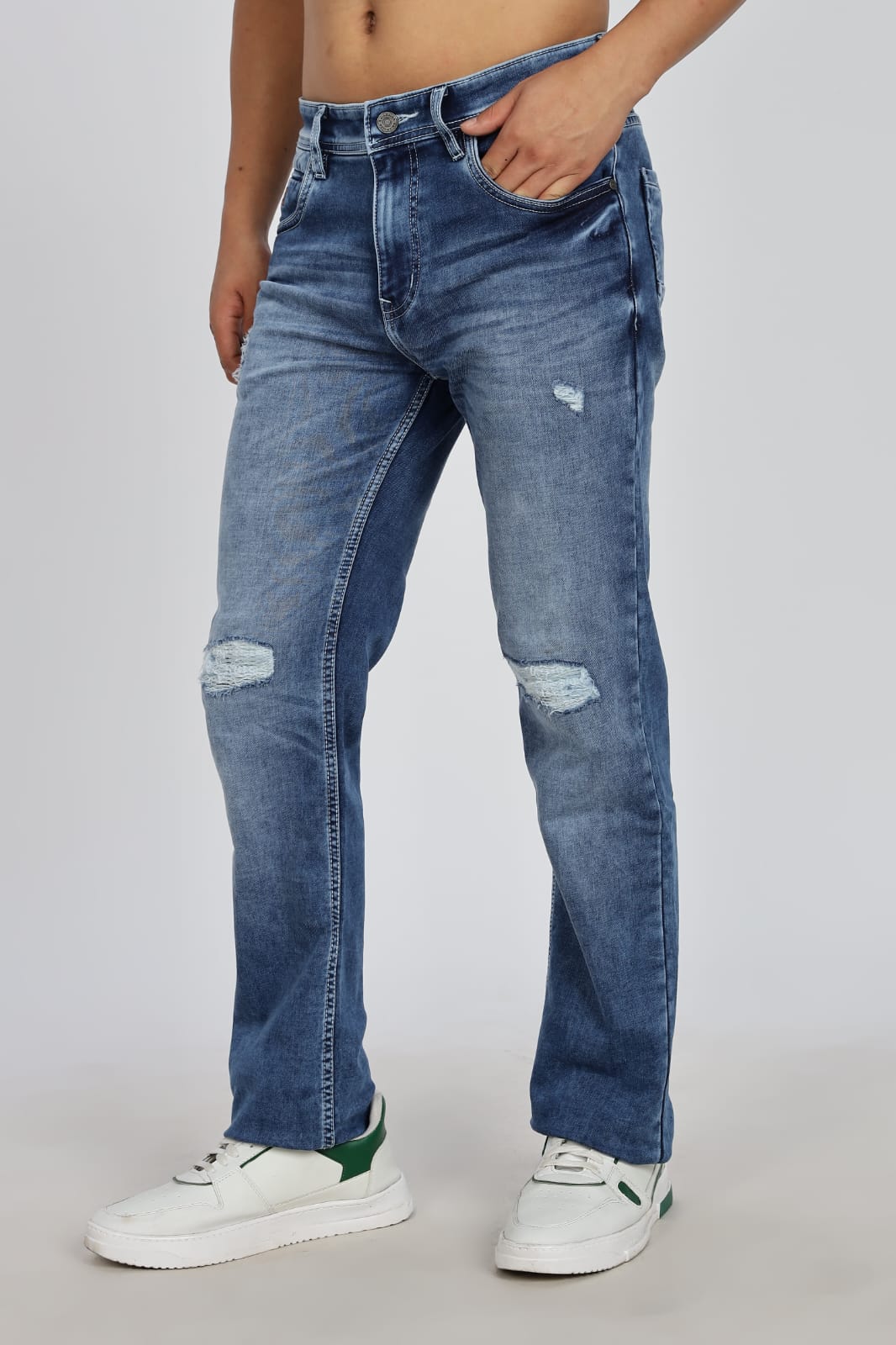 Person wearing blue distressed jeans on a plain background