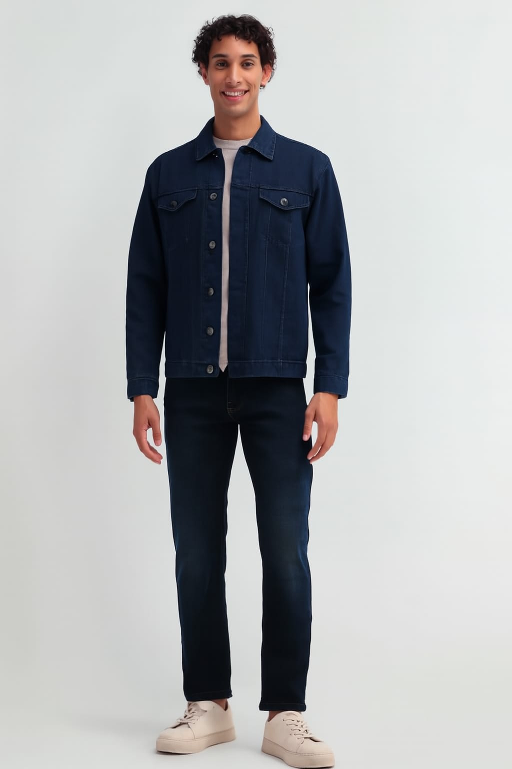 Man wearing a navy blue jacket and dark jeans on a white background