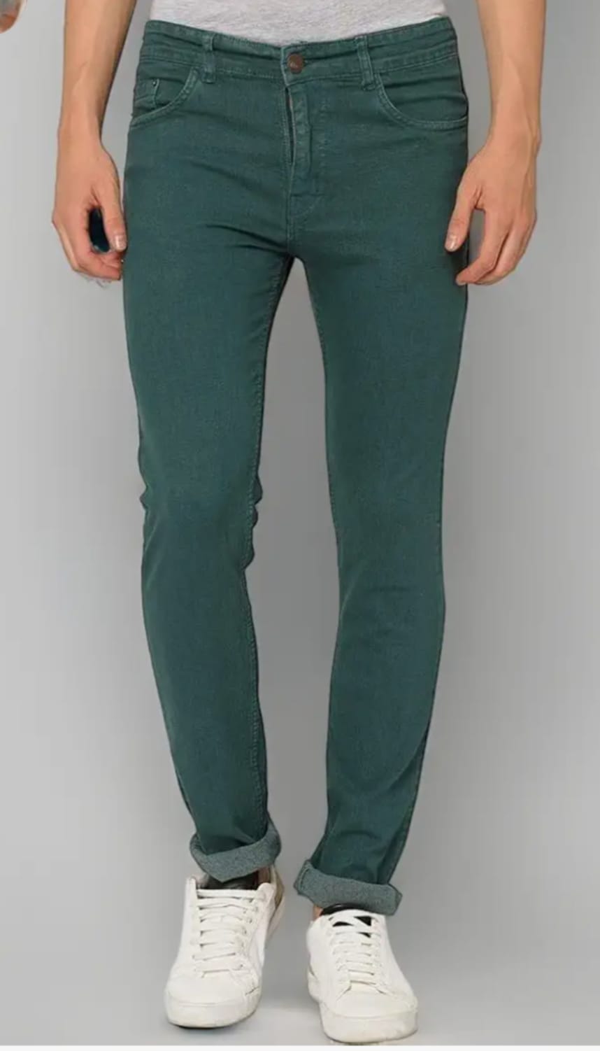 Person wearing teal pants and white sneakers on a gray background