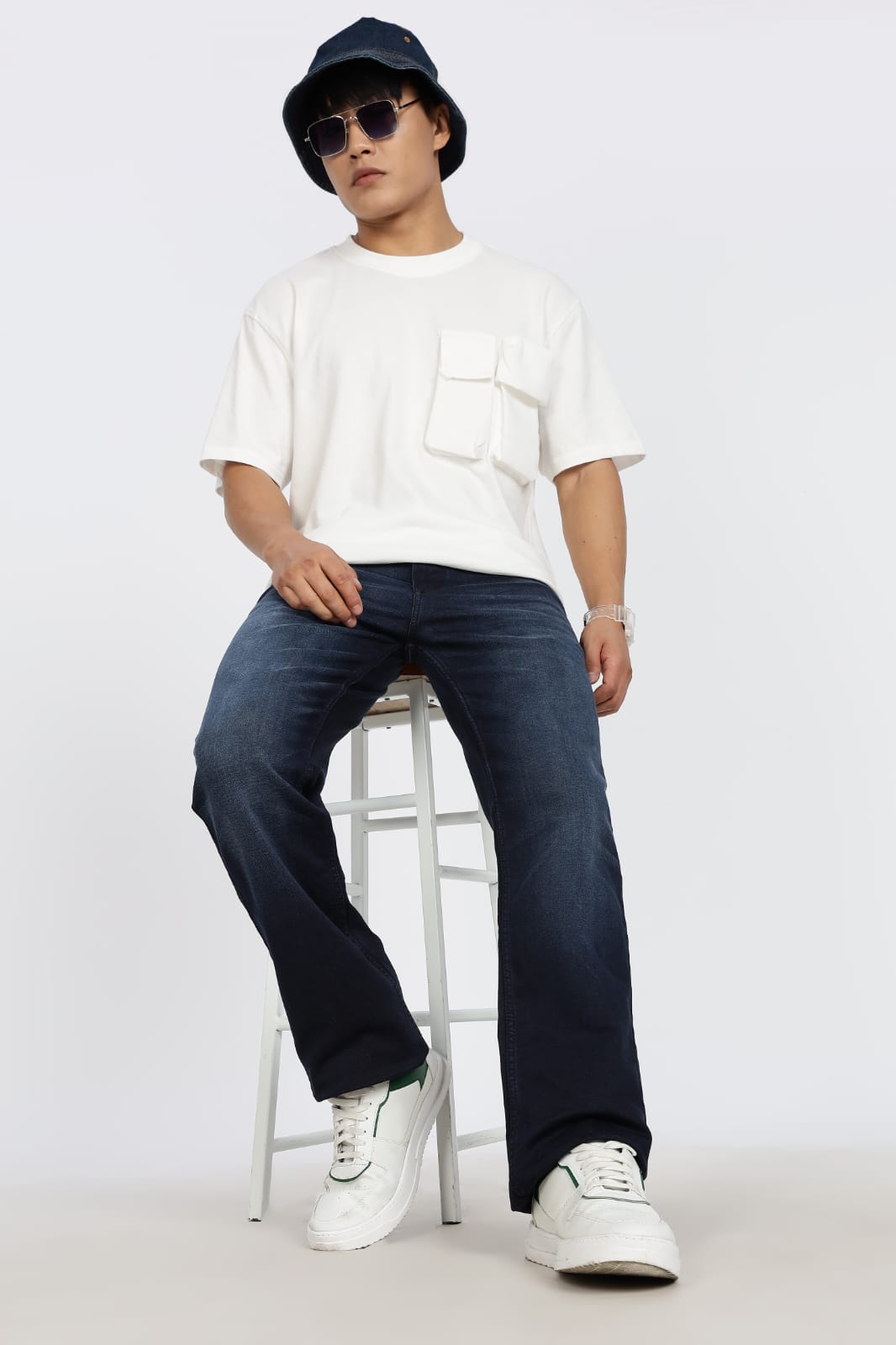 Person wearing a white t-shirt, dark jeans, and a cap on a white background