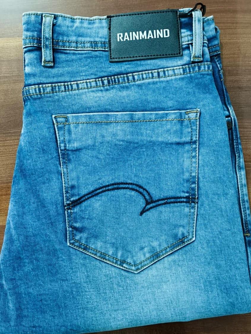 Blue jeans with a 'Rainmaid' tag on a wooden surface