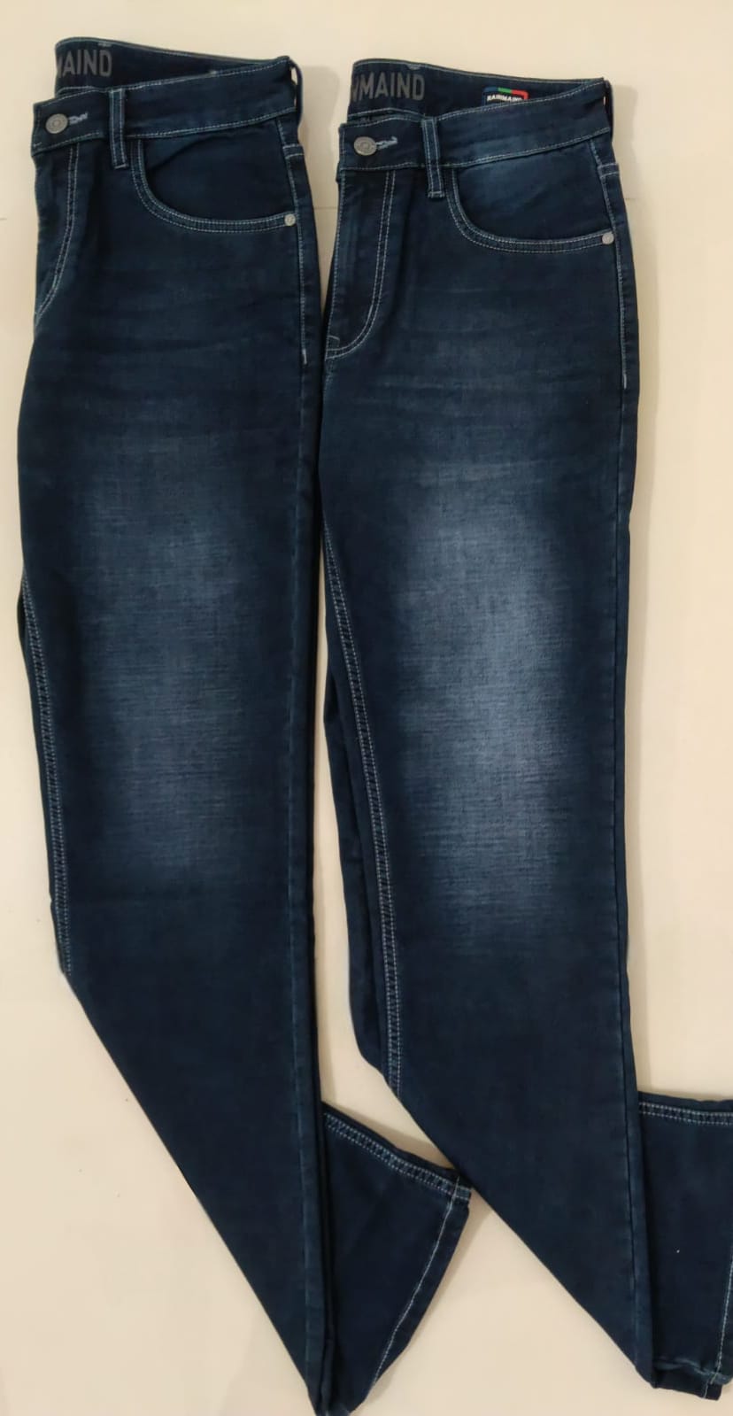 Pair of dark blue jeans on a beige background