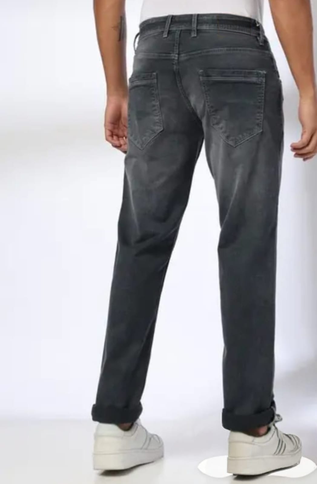 Person wearing dark gray jeans on a white background