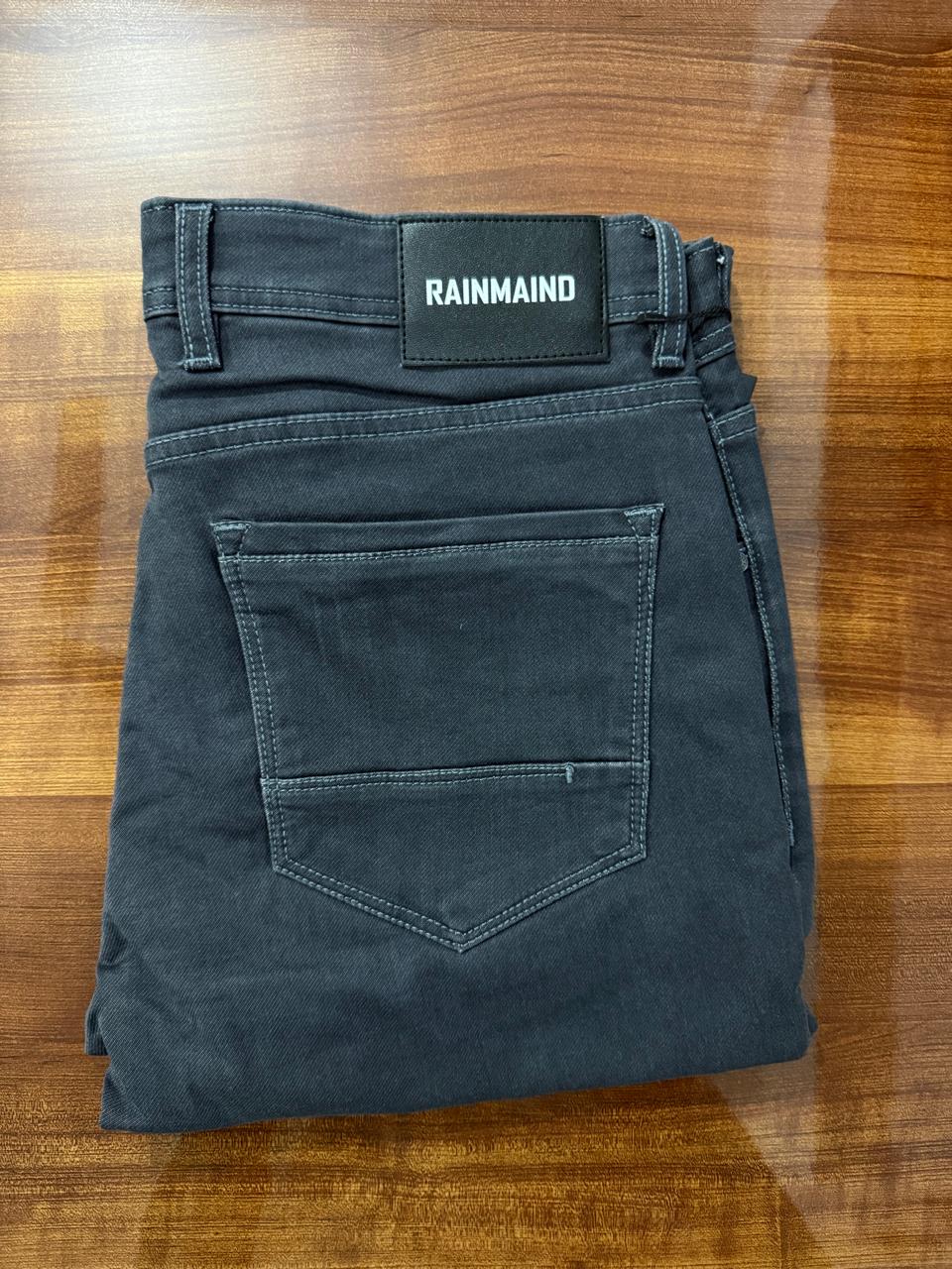 Folded black pants with 'RAINMAID' label on a wooden surface