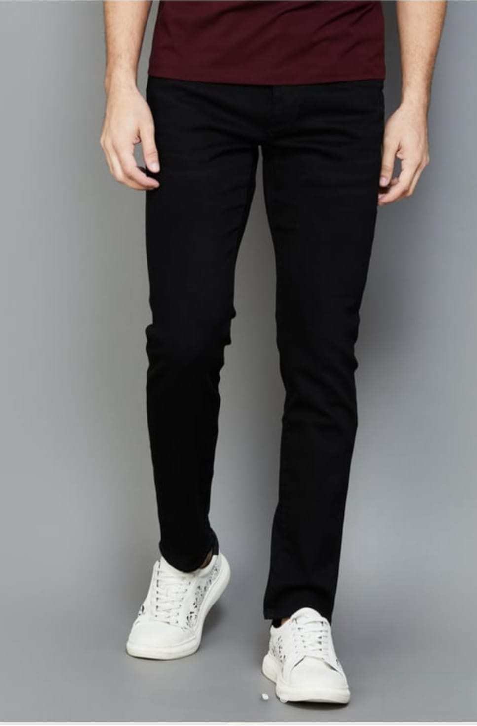 Person wearing black pants and white sneakers on a gray background