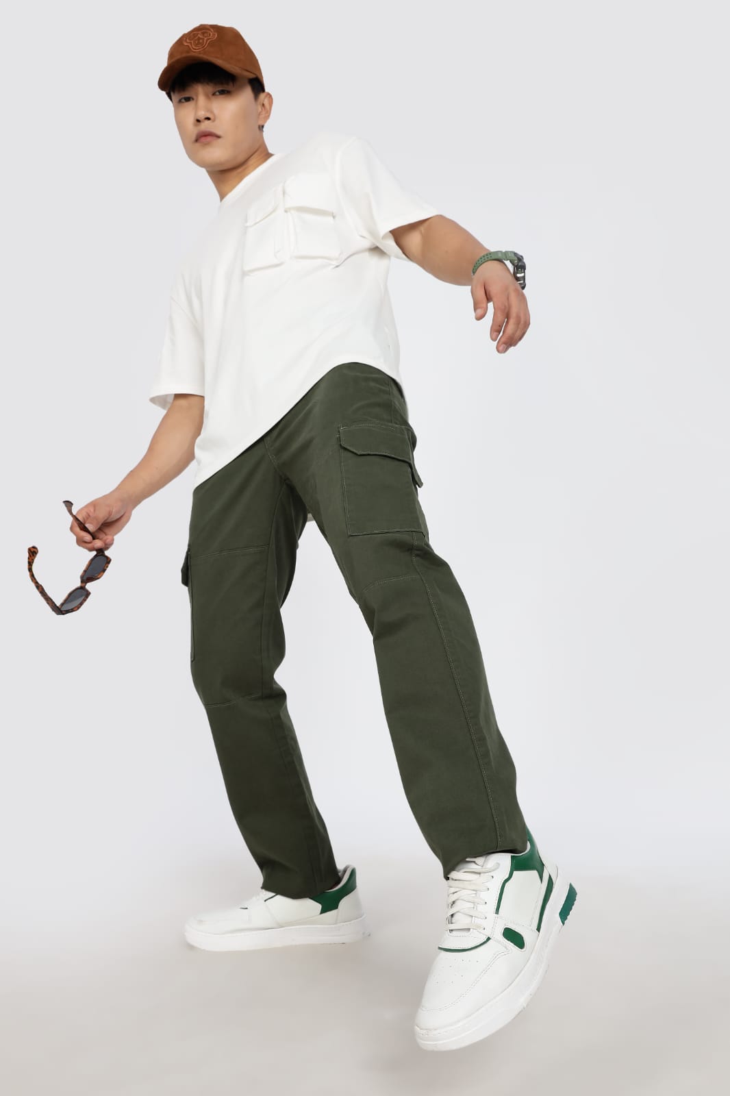 Person wearing a white shirt, green cargo pants, and white sneakers on a plain background