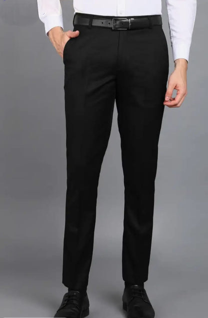 Person wearing black dress pants with a plain background