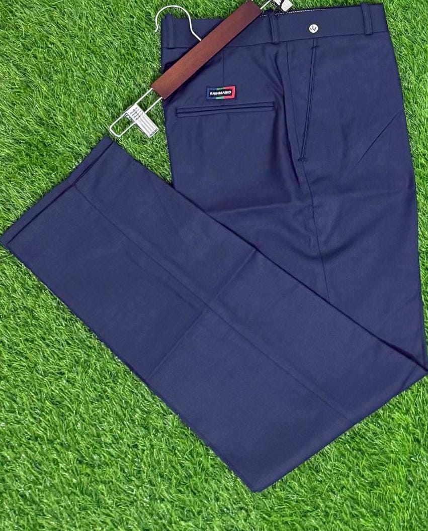 Navy blue pants on a hanger with a brand label against a grass background