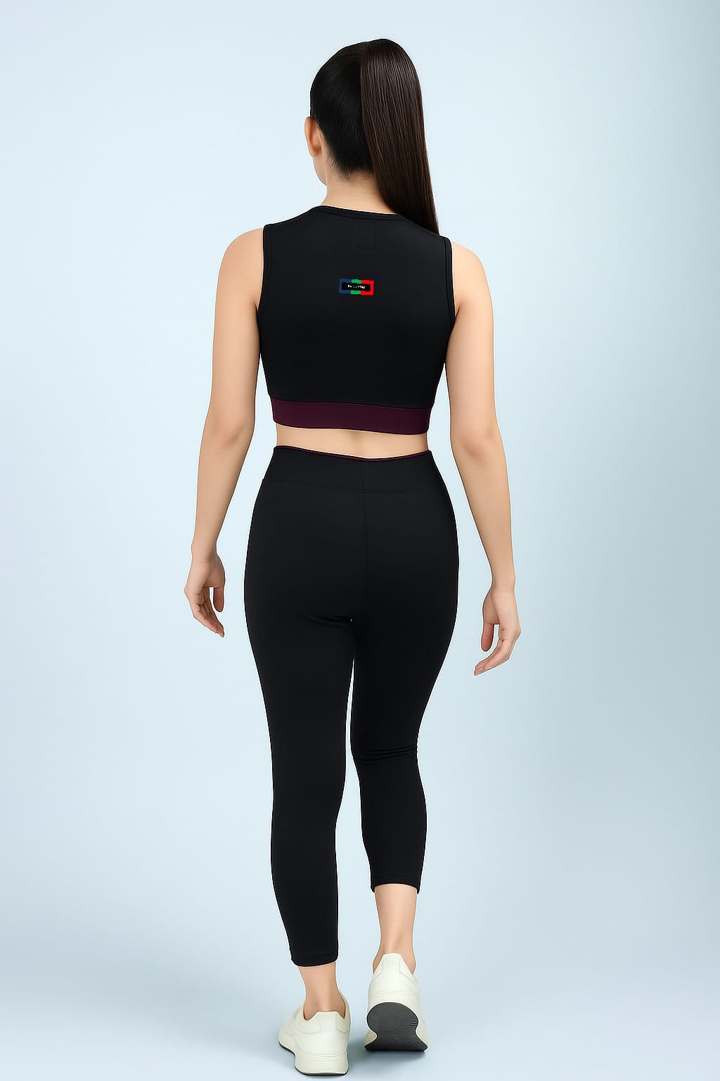 Person wearing a black sleeveless top and leggings on a light gray background