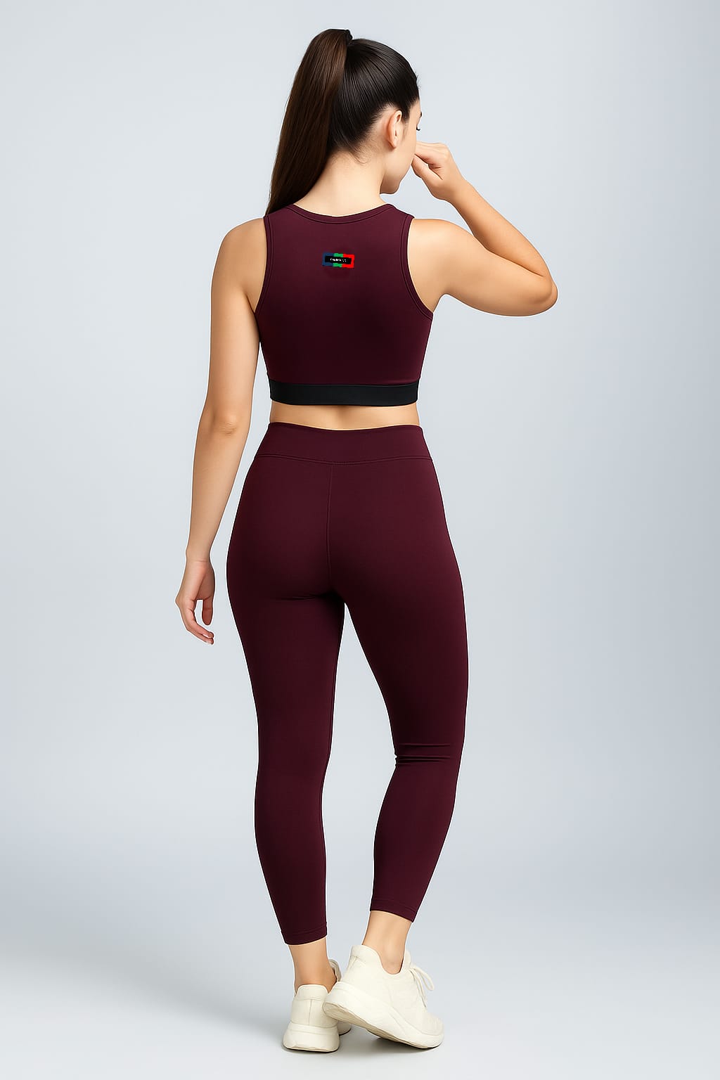 Woman wearing a maroon athletic outfit with a logo on a light gray background