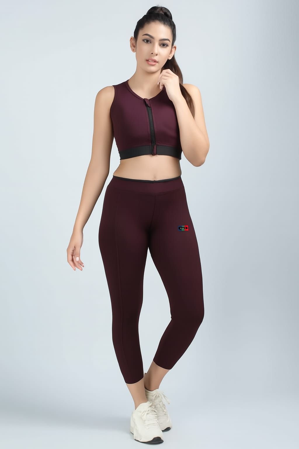 Woman wearing a maroon athletic outfit with a logo on a light gray background
