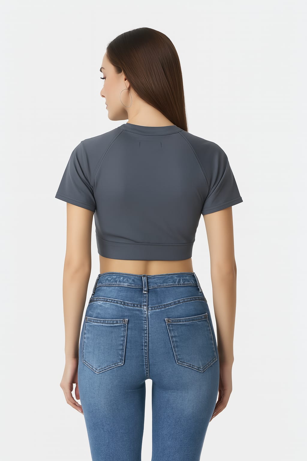 Woman wearing a gray crop top and blue jeans on a white background