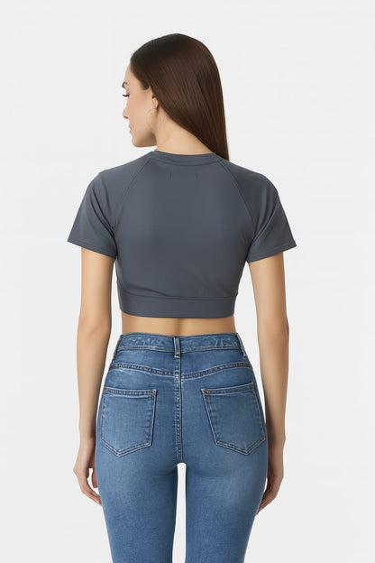 Woman wearing a gray crop top and blue jeans on a white background