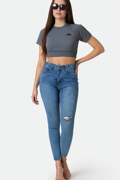 Woman wearing a gray crop top and blue jeans on a white background
