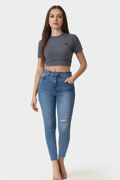 Woman wearing a gray crop top and blue jeans on a white background