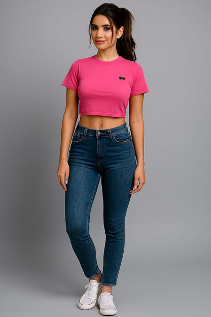 Person wearing a pink crop top and blue jeans on a gray background