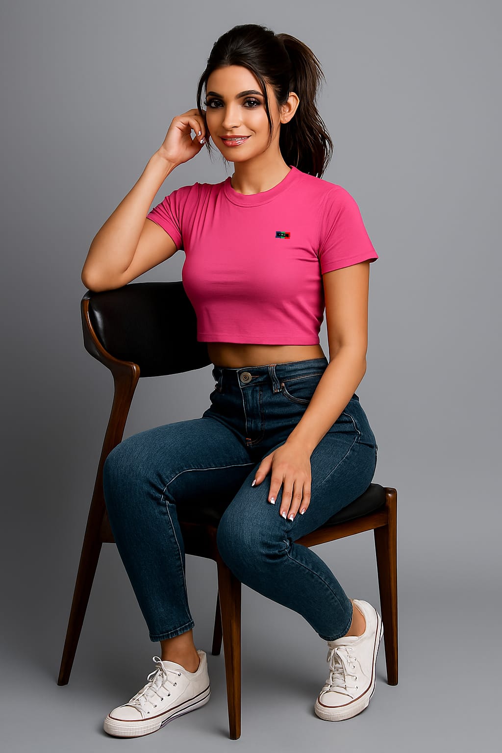 Person wearing a pink crop top and blue jeans on a gray background