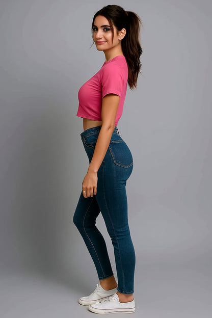 Person wearing a pink crop top and blue jeans on a gray background